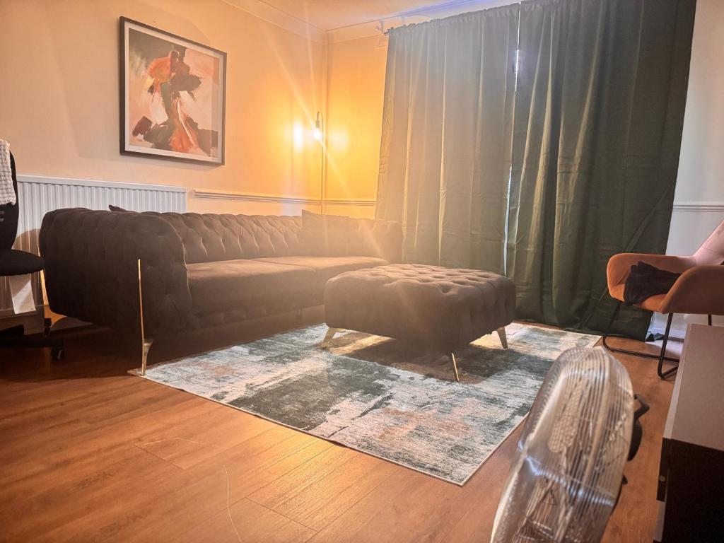 een woonkamer met een bank en een poef bij Cozy Nest in Grays Thurrock