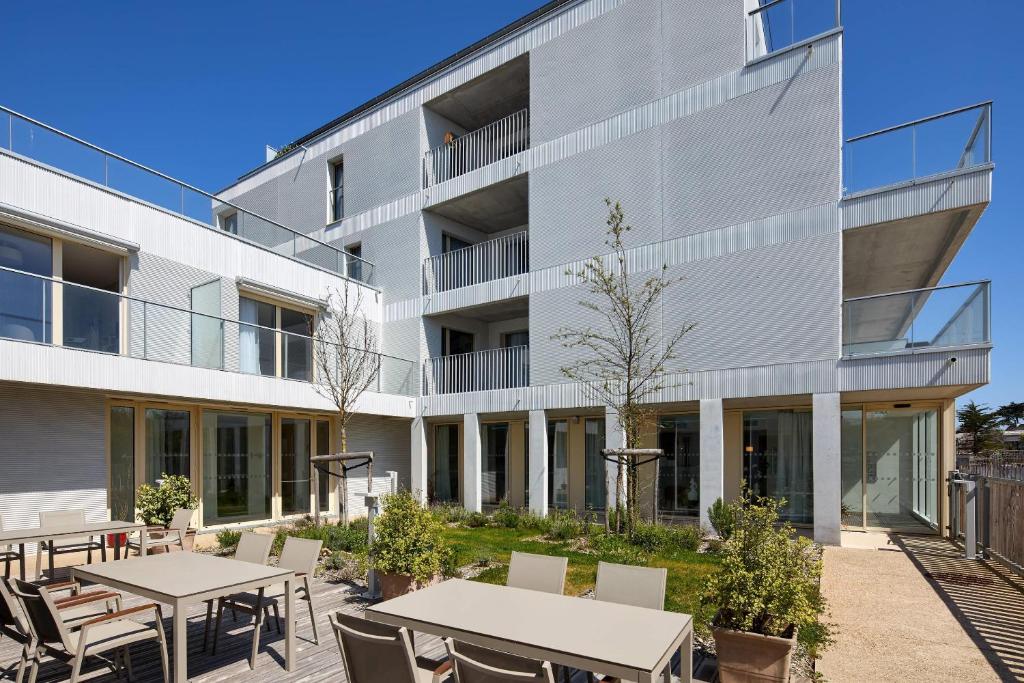 uma vista externa de um edifício com mesas e cadeiras em Quality Suites Quiberon em Quiberon