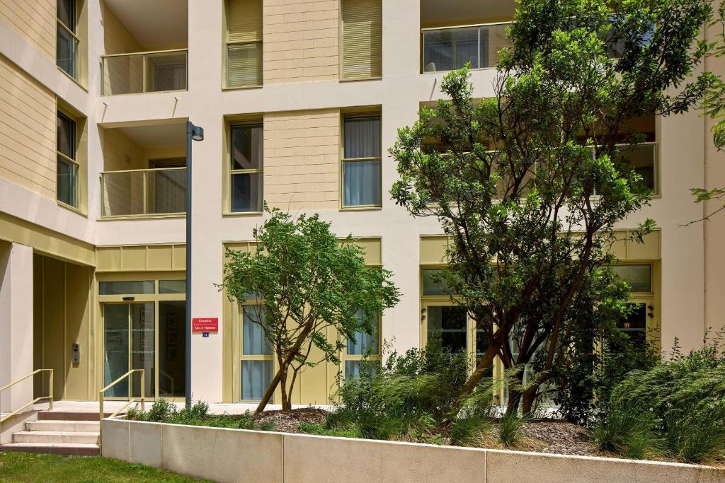 Un edificio de apartamentos con árboles en frente. en Quality Suites Bordeaux Saint-Jean, en Burdeos