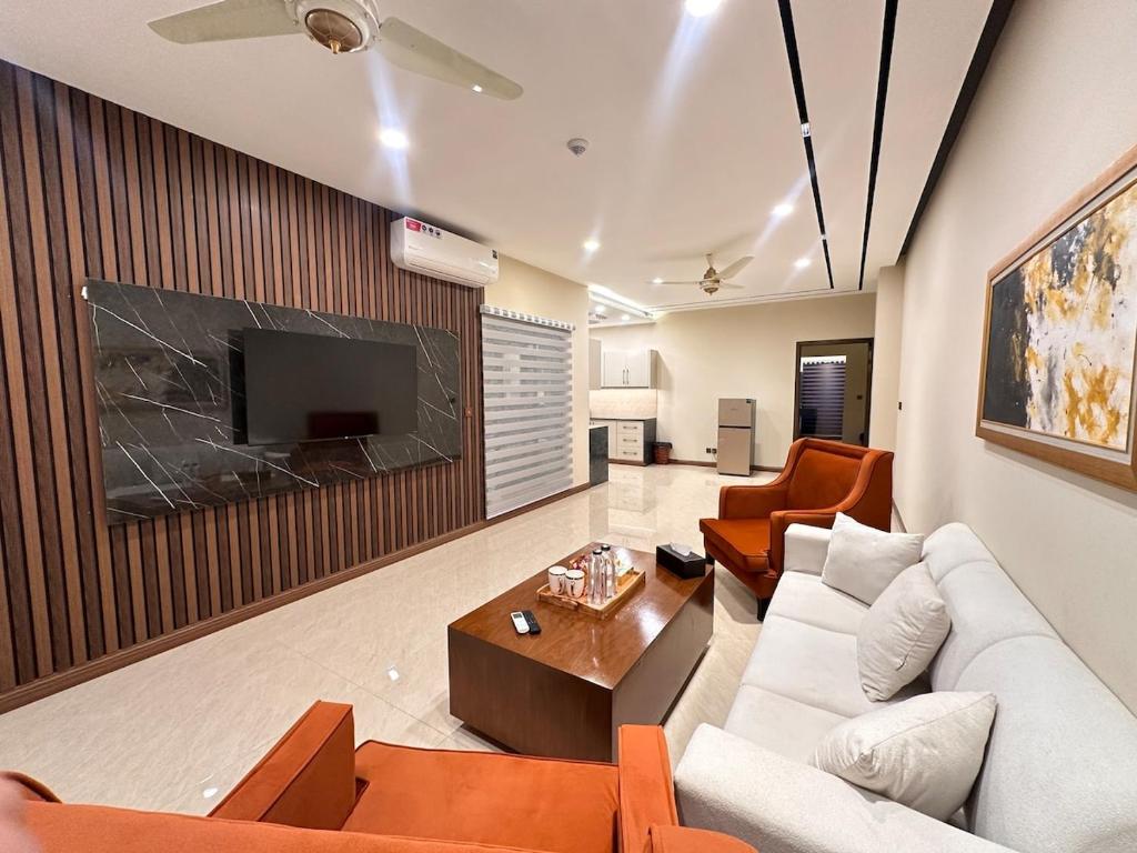 een woonkamer met een bank en een tv bij Zeta Mall 2 bedroom Apartment with Swimming Pool in Islamabad