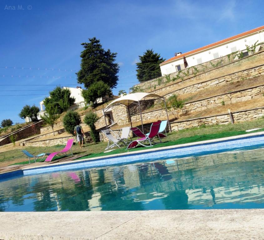 a swimming pool with chairs and a gazebo at Douro Natura in Bemposta