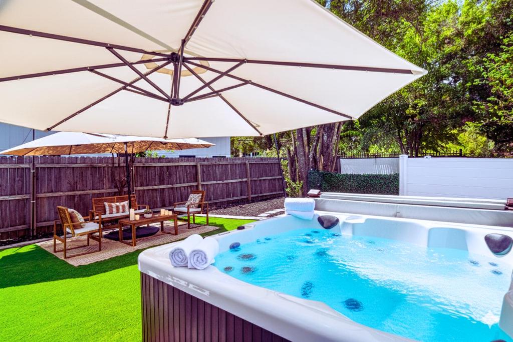 a hot tub in a backyard with an umbrella at Central East Austin Luxury Hot Tub & Game Room in Austin