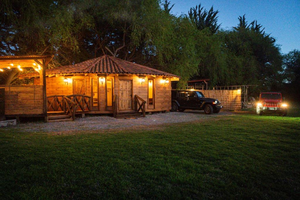 a wooden cabin with a car parked in a yard at night at Antu Wellness cabaña de lujo en paine in Maipo