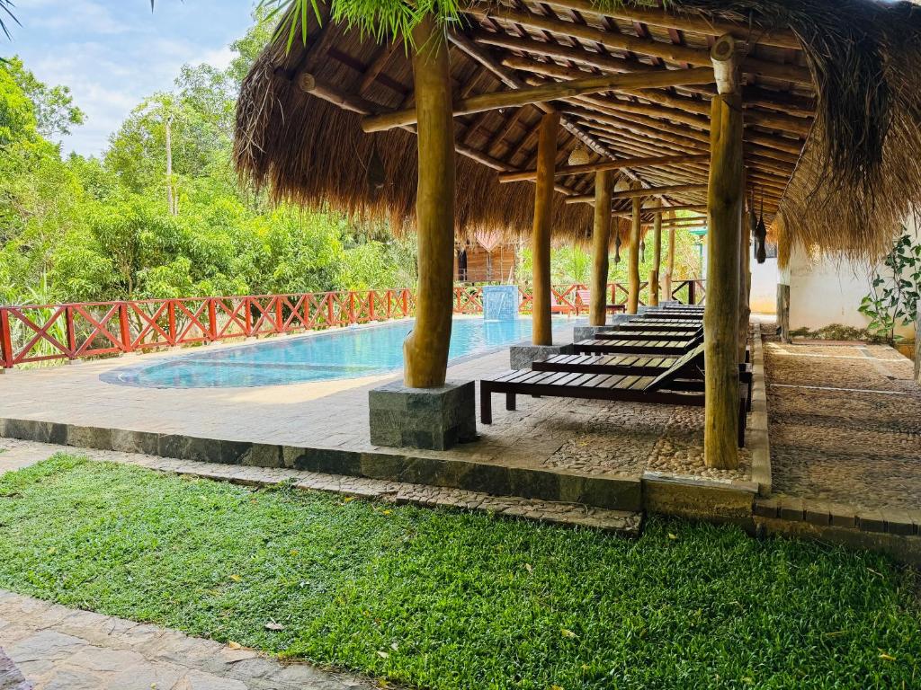 a resort with a swimming pool and a straw umbrella at Sunrise Udawalawe Resort in Udawalawe