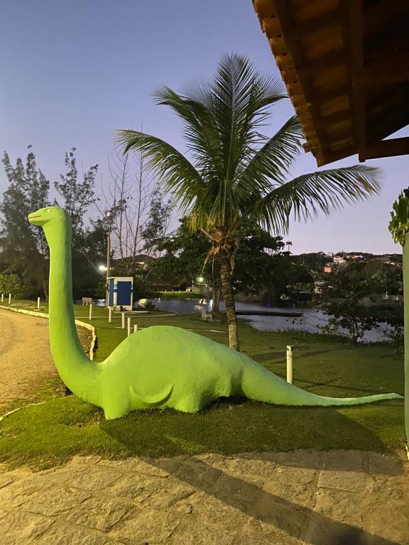 a dinosaur statue sitting on the grass near a palm tree at Pousada Ferradura Beach in Búzios
