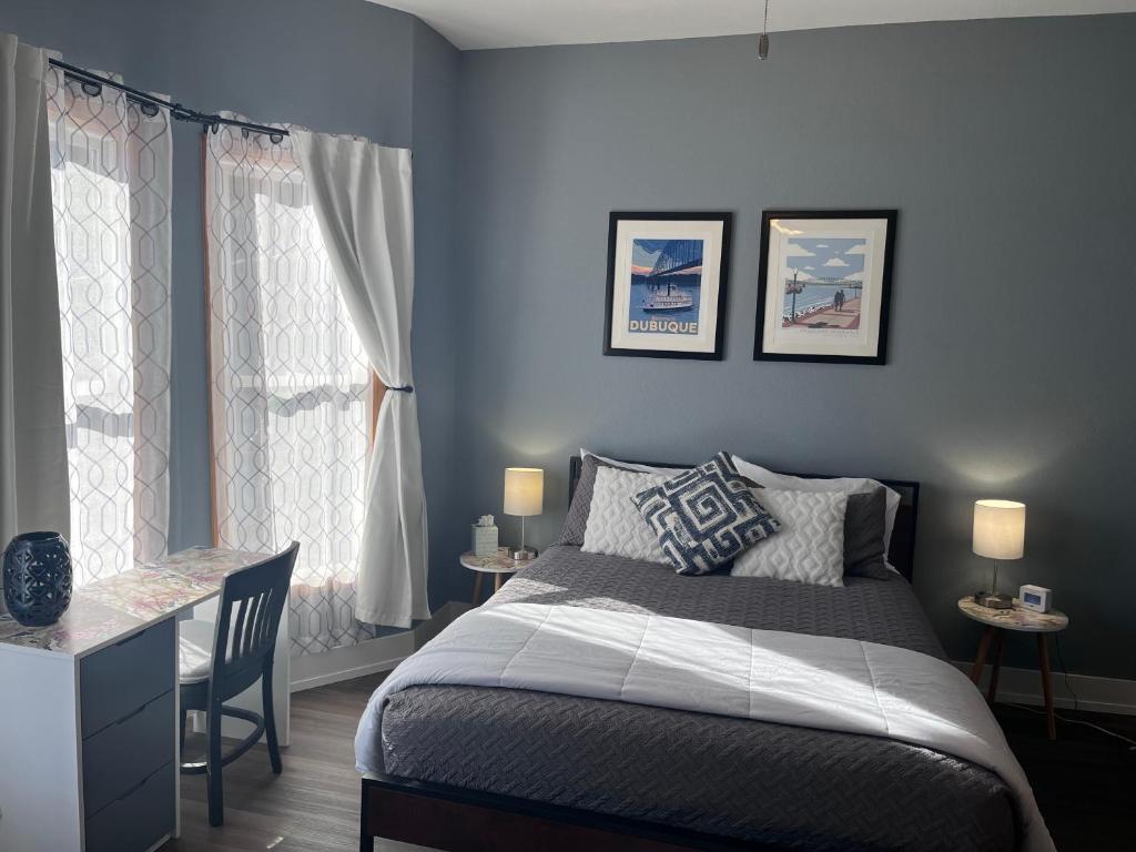 ein Schlafzimmer mit einem Bett und einem Schreibtisch und zwei Fenstern in der Unterkunft Relaxing Townhouse Downtown Dubuque in Dubuque