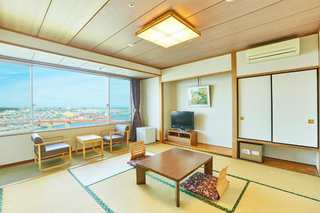a living room with a table and a large window at KAMENOI HOTEL Oarai in Oarai