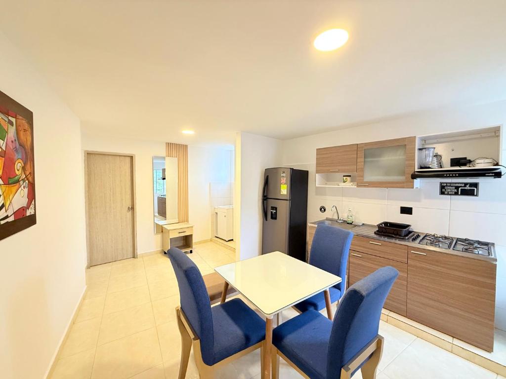 a kitchen with a table and blue chairs in a room at The Host apartamentos At Los Angeles in Santa Marta