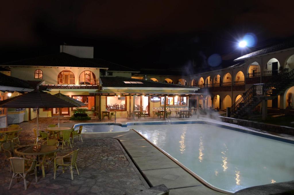 una piscina por la noche con mesas y sillas en Hosteria Duran, en Cuenca
