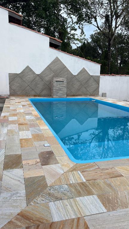 a swimming pool in front of a house with a tile floor at Chalé Bromélia in São Sebastião