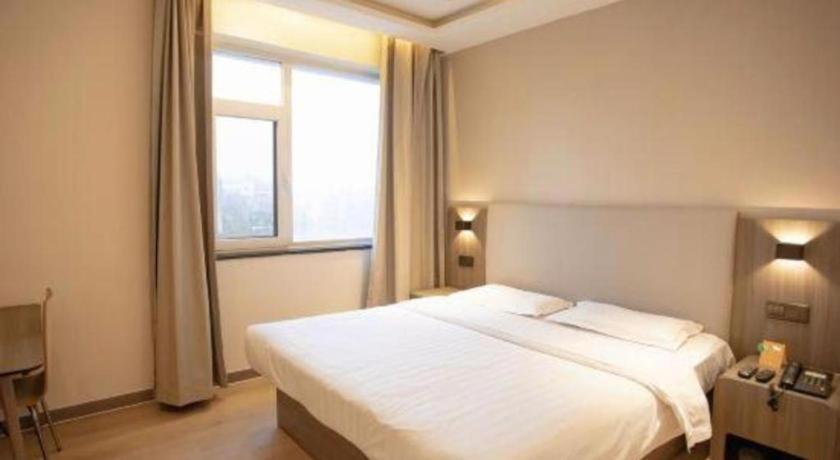 une chambre avec un grand lit blanc et une fenêtre dans l'établissement 7 Days Inn Tianjin Binhai Passenger Station Huabei Ceramics, à Binhai