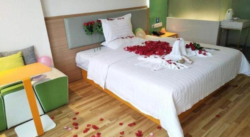 a bedroom with a white bed with red flowers on it at 7Days Inn Tianjin Airport NO.1 Bridge Branch in Tianjin