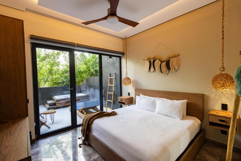 a bedroom with a bed and a large window at Tulum Escape - Private Hot Tub, Steps to Free Beach in Tulum