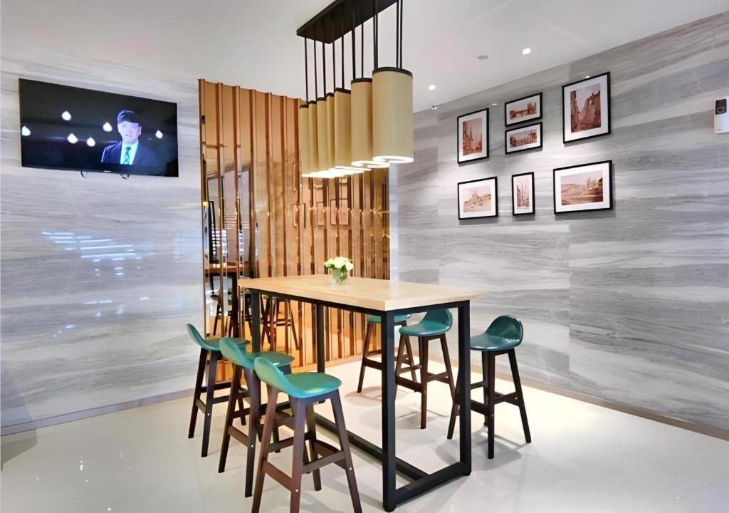 ein Esszimmer mit einem Tisch und grünen Stühlen in der Unterkunft City Comfort Inn Dongguan Zhongtang in Zhongtang