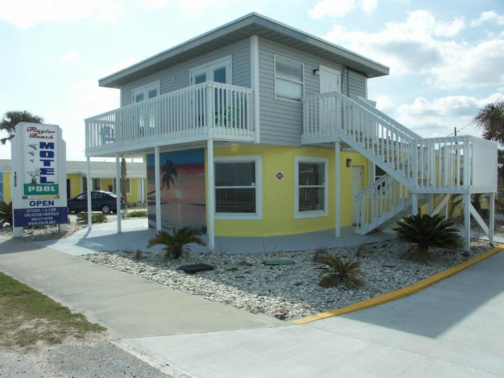 uma pequena casa amarela com uma escada branca em Flagler Beach Motel and Vacation Rentals em Flagler Beach