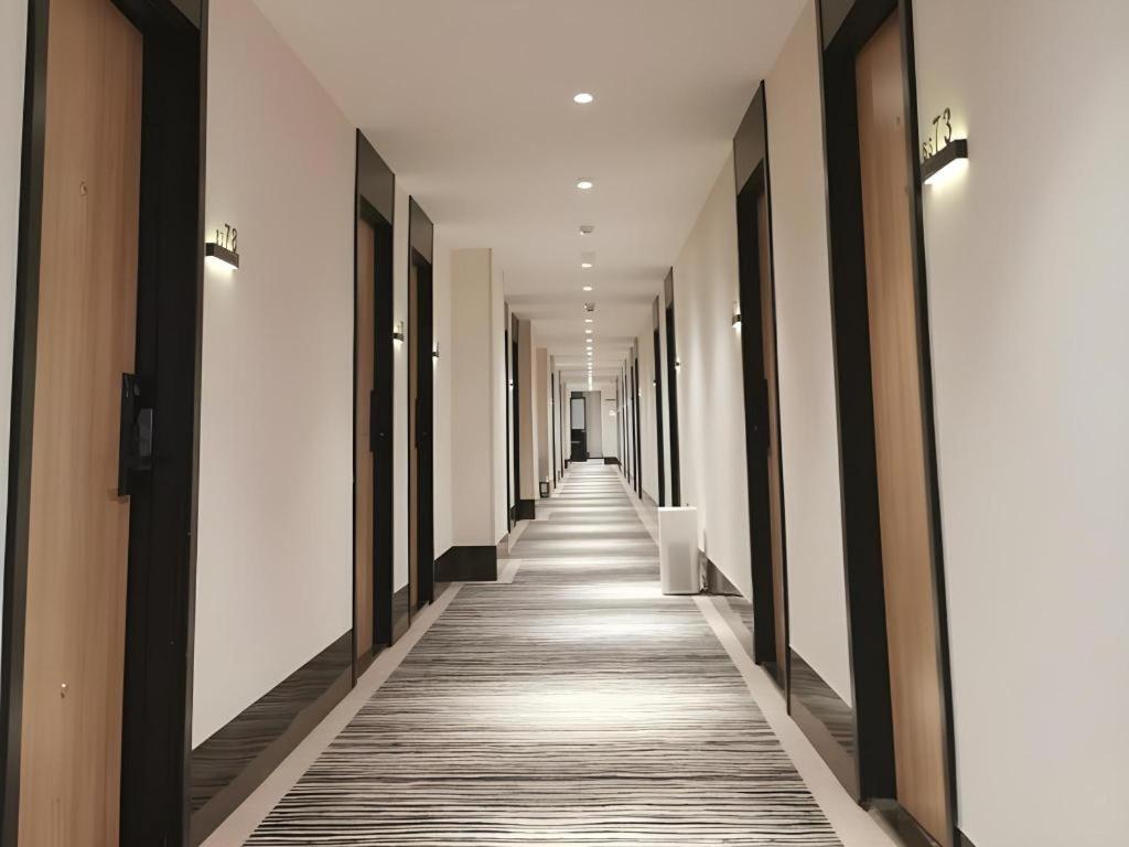 einen Flur eines Gebäudes mit weißen Wänden und Holzböden in der Unterkunft Green Tree Inn Express Shanghai Bund Yuyuan Xiaonanmen Metro Station in Shanghai