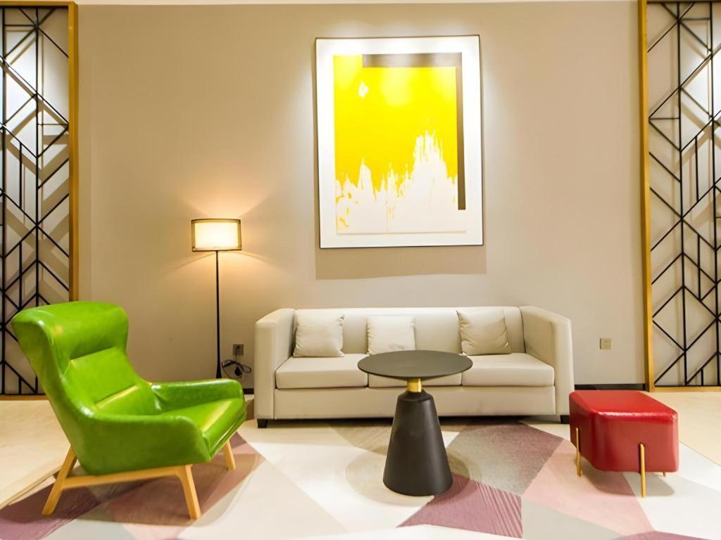 a living room with a couch and a table and a green chair at Borrman Hotel Zhongshan Henglan Xiyong in Changzhou