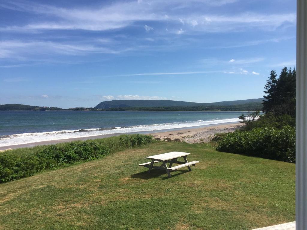 a picnic table sitting on the grass near the beach at Lantern Hill & Hollow in Ingonish Beach