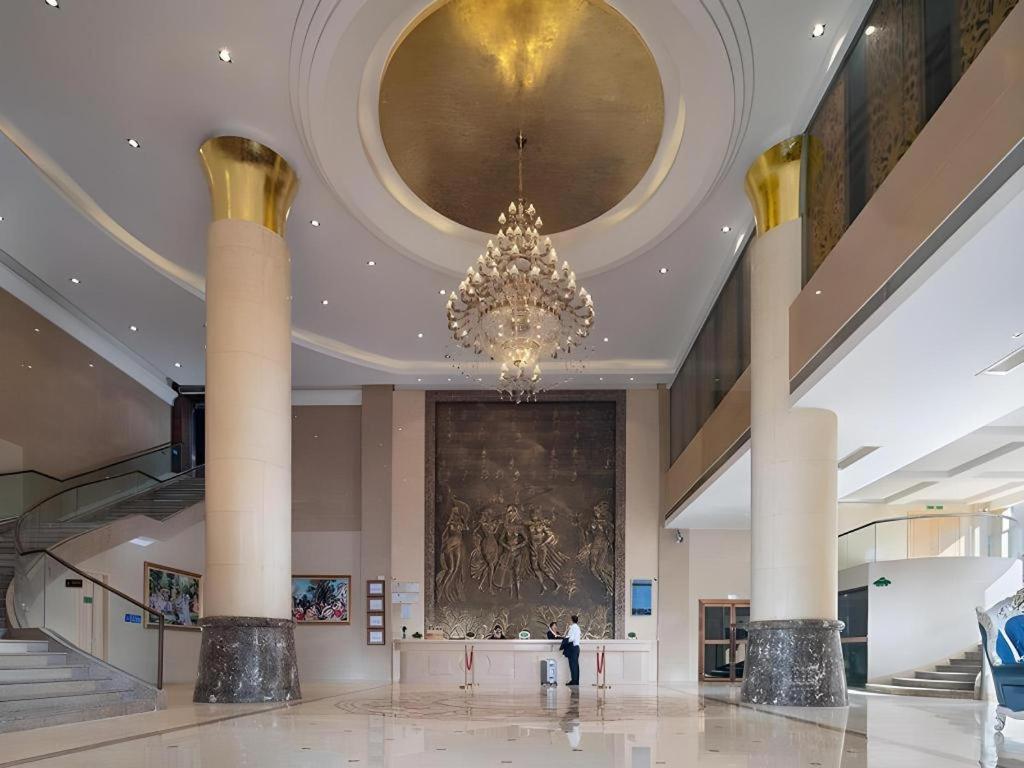 eine große Lobby mit einem Kronleuchter in einem Gebäude in der Unterkunft Vienna Hotel Guangdong Foshan West Station Airport Luocun in Huanshi