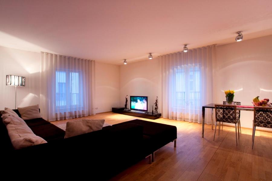 een woonkamer met een zwarte bank en een televisie bij Tatari Apartment in Tallinn