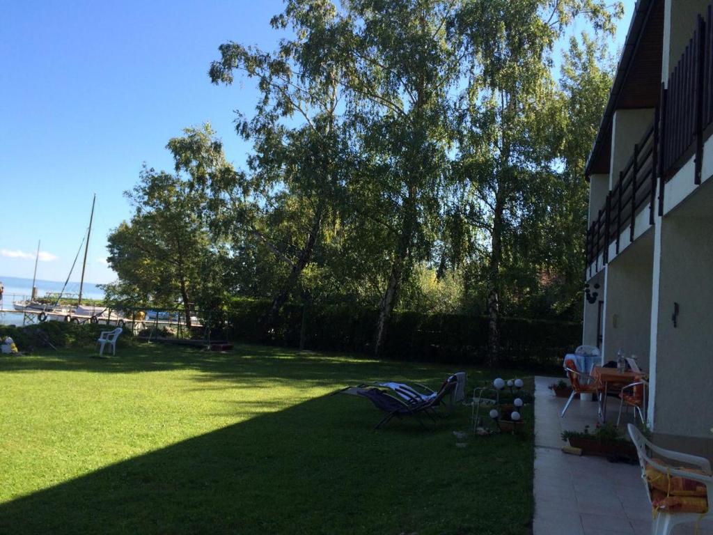 a backyard with a lawn with chairs and trees at Attila Beach Boglár in Balatonboglár