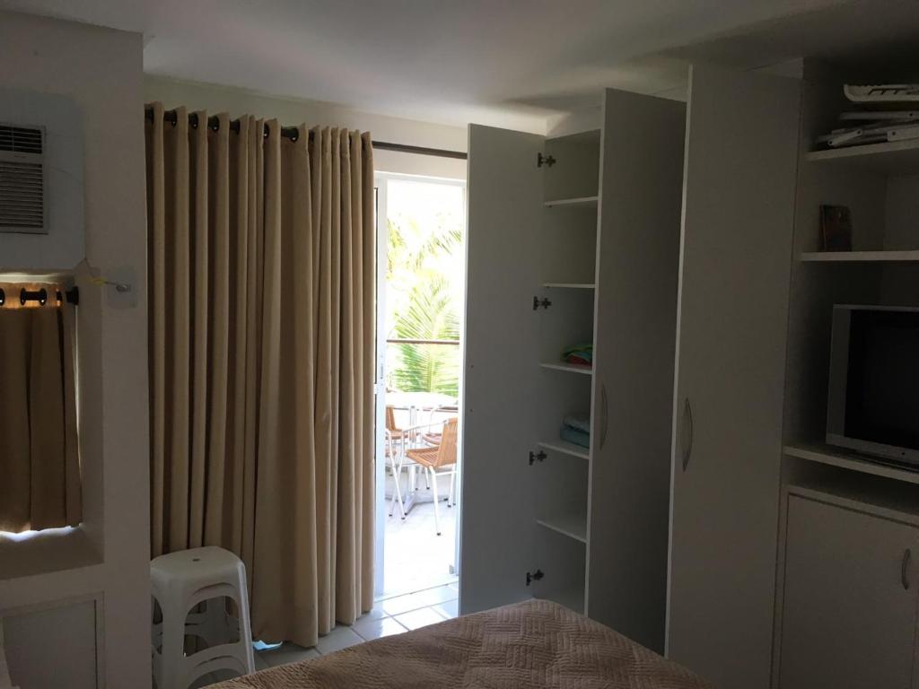 1 dormitorio con 1 cama y puerta con ventana en Ancorar Flat Resort 2207 B, en Porto de Galinhas