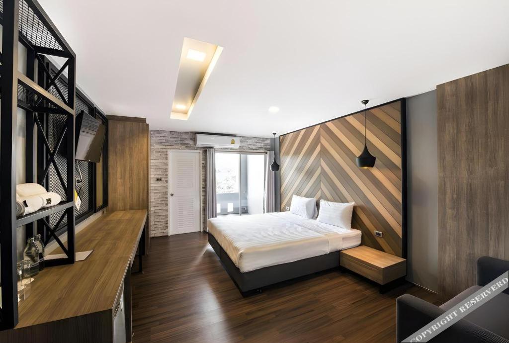 ein Schlafzimmer mit einem Bett und einer Holzwand in der Unterkunft The Circle Hotel in Ban Bu Lamduan