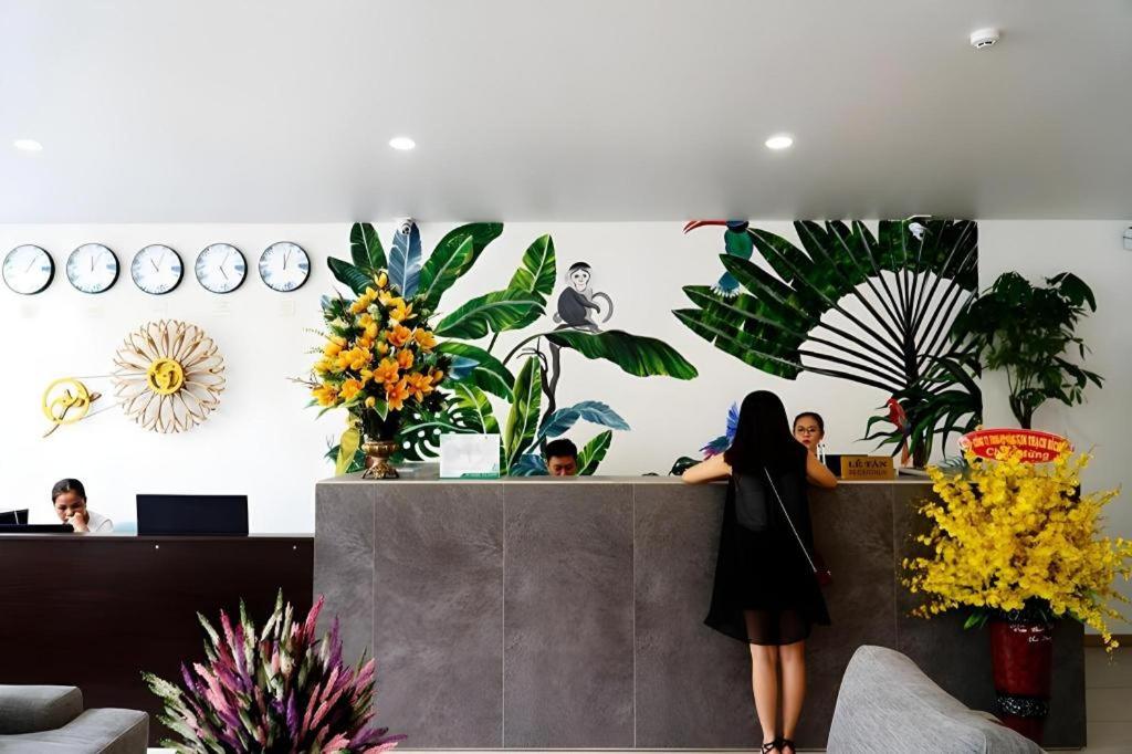 a woman standing at a counter in a room with plants at Green Oasis Hotel in Phường Sáu