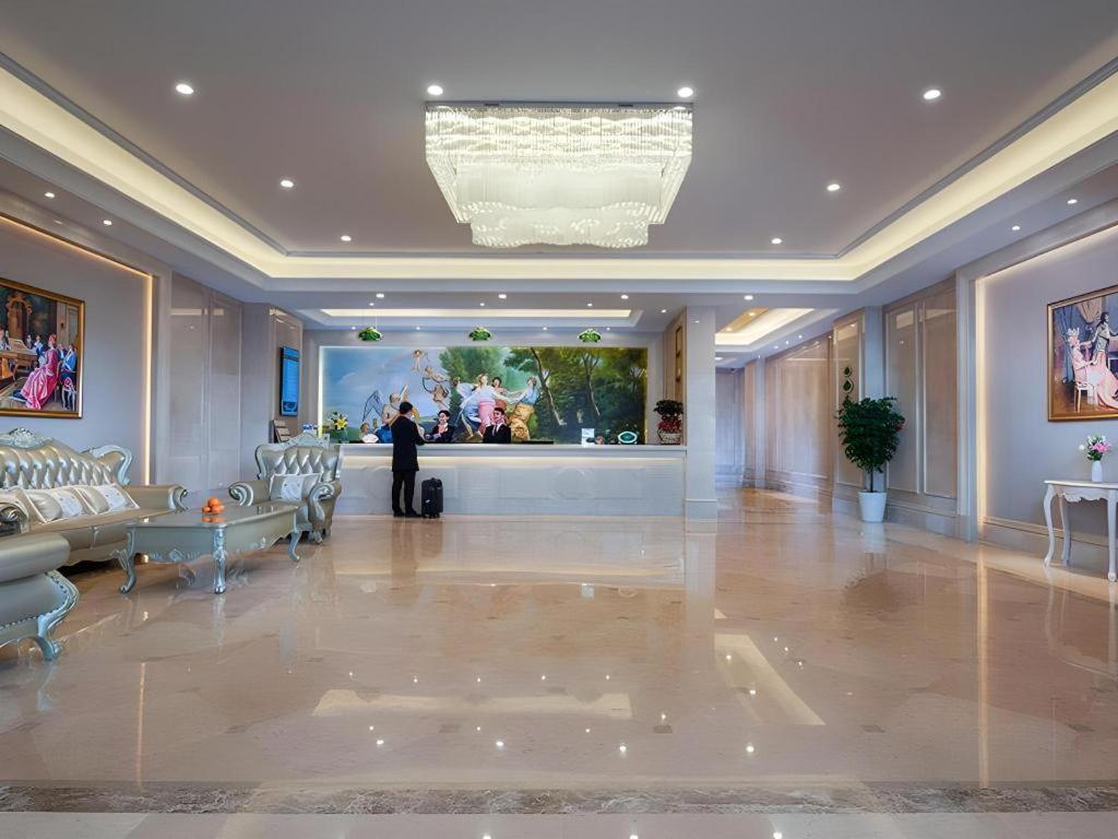 ein Mann steht in einer Lobby mit einem Gemälde an der Wand in der Unterkunft Vienna Hotel Nanning Xiangsi Lake University Town in Nanning