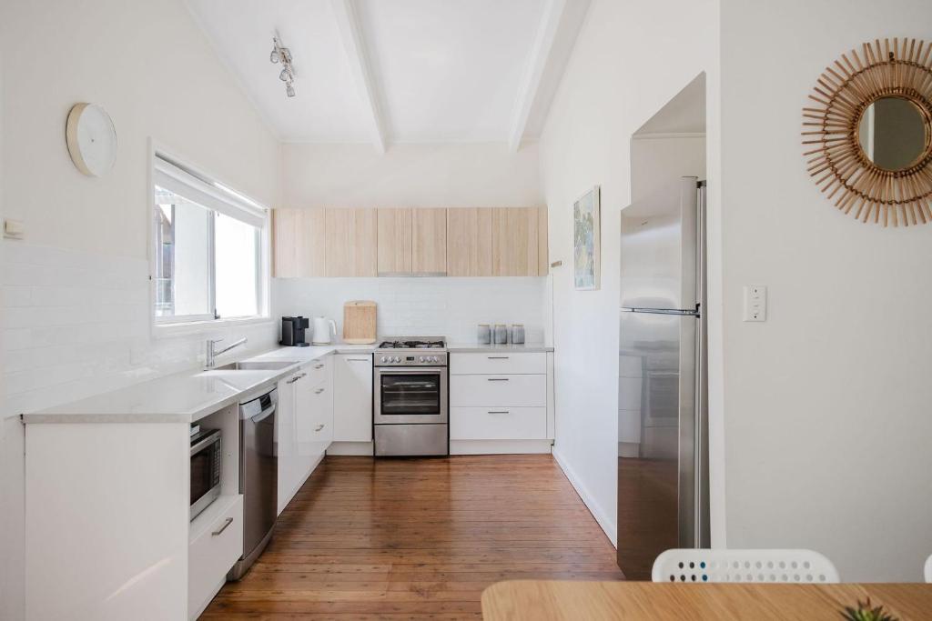 a kitchen with white appliances and a wooden floor at Medona - Narrawallee Beach House in Narrawallee
