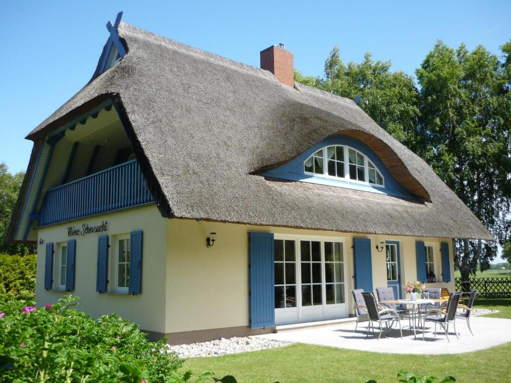 ein strohgedecktes Haus mit einem Tisch und Stühlen in der Unterkunft Ferienhaus Mine Sehnsucht in Dierhagen