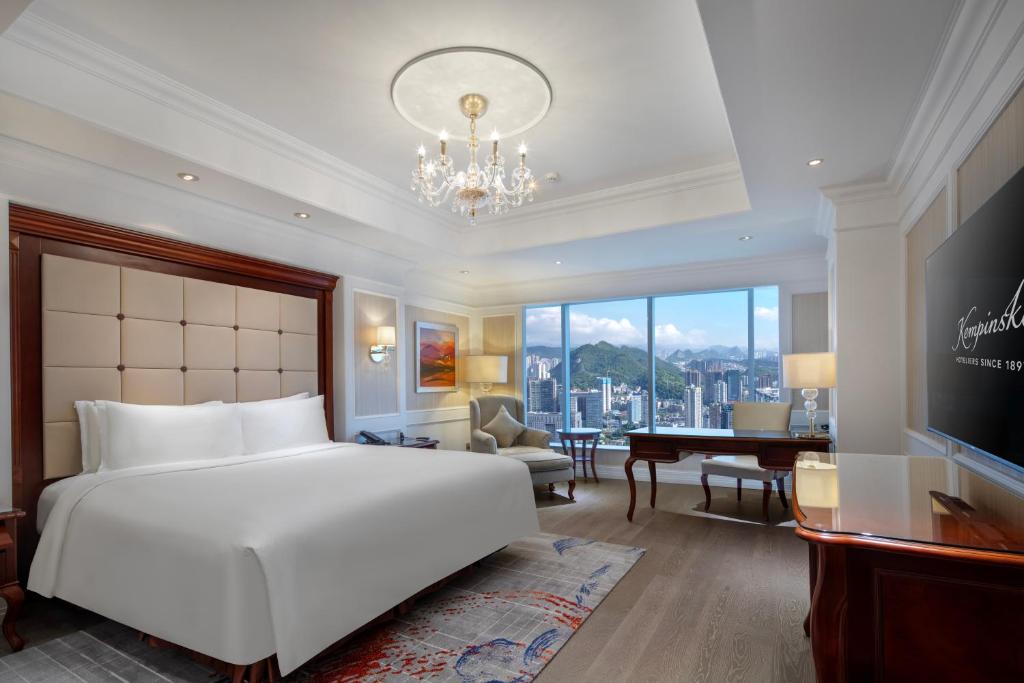 a bedroom with a large white bed and a desk at Kempinski Hotel Guiyang in Guiyang