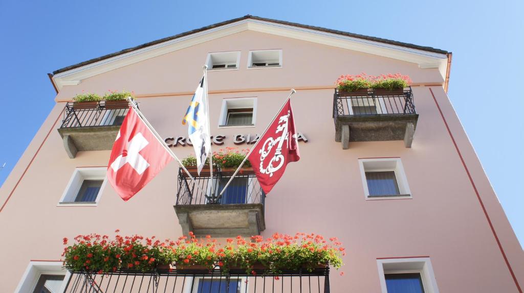 un bâtiment avec drapeaux et fleurs devant lui dans l'établissement Albergo Croce Bianca, à Poschiavo