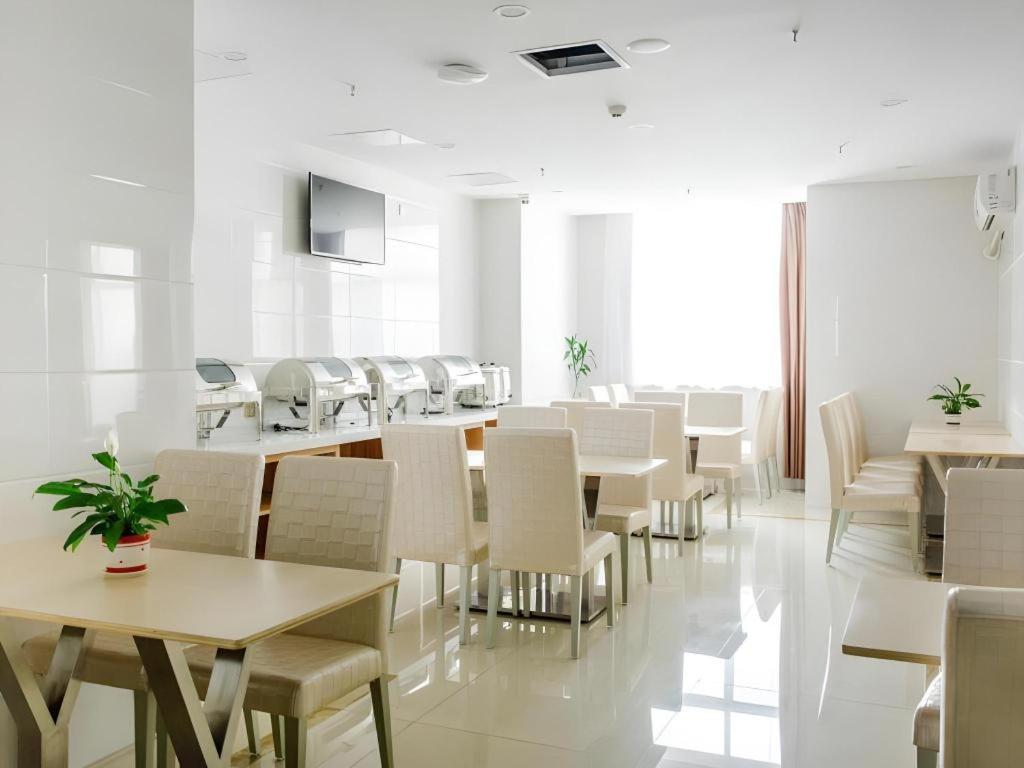 ein Esszimmer mit weißen Tischen und weißen Stühlen in der Unterkunft GreenTree Inn Wuxi Huishan District Xizhang Metro Station Express Hotel in Wuxi