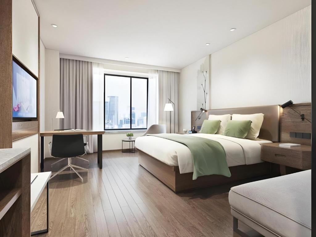 a bedroom with a large bed and a desk with a computer at GreenTree Inn Ganzhou Gan County Bus Station in Meilin