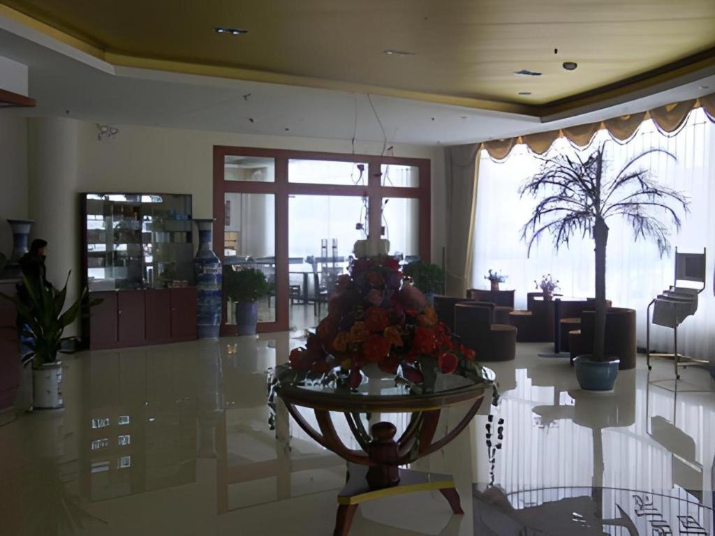 eine Lobby mit einem Tisch mit Blumen darauf in der Unterkunft GreenTree Inn Heze Railway Station Hotel in Zhaolou