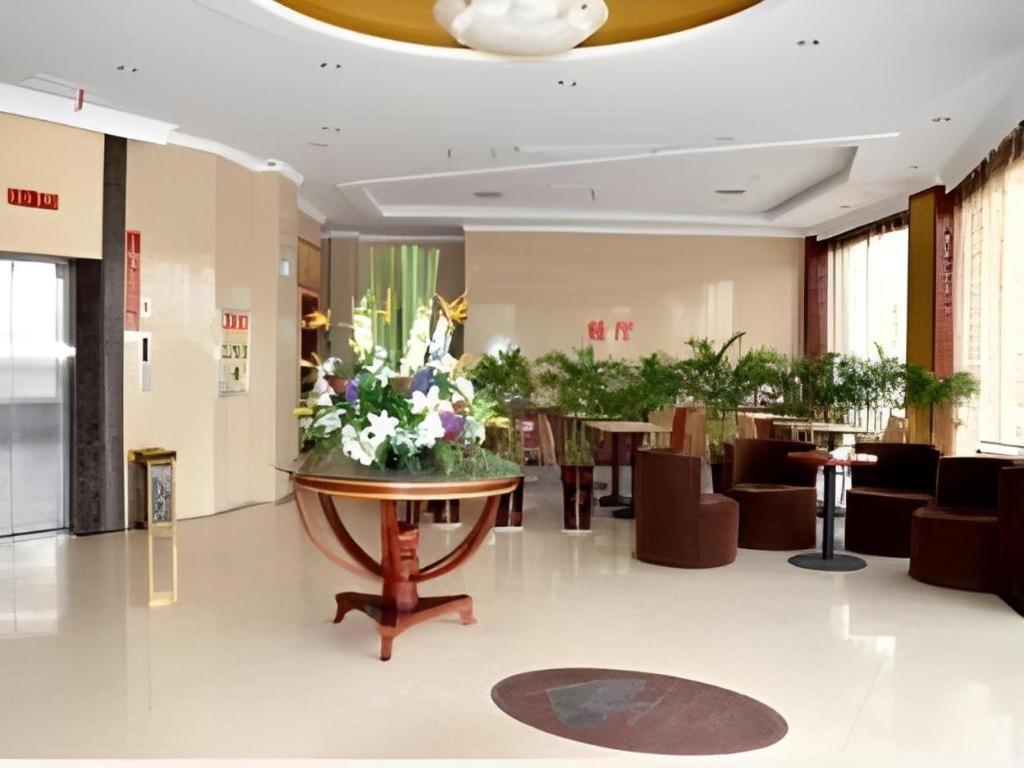 eine Lobby mit einem Tisch mit Blumen darauf in der Unterkunft GreenTree Inn Jiaxing Tongxiang Tudian Express Hotel in T'u-tien-shih