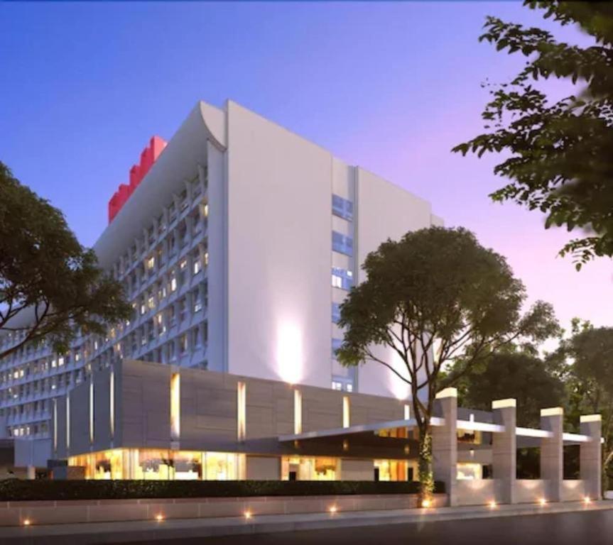 a large white building with a tree in front of it at Elmi Hotel in Surabaya