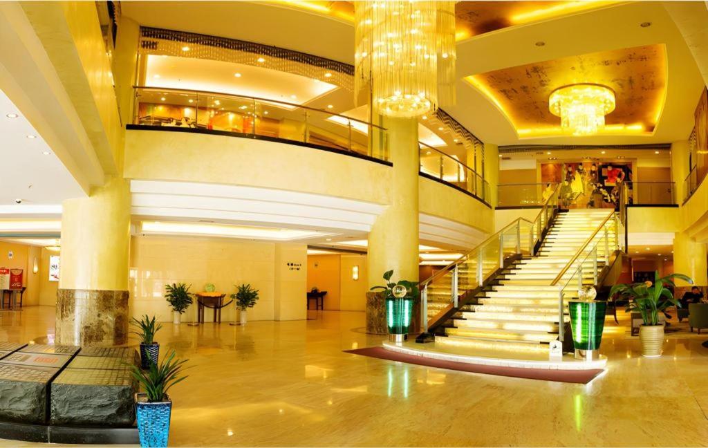 eine große Lobby mit einer Treppe in einem Gebäude in der Unterkunft Qingdao Blue Horizon Hotel Laoshan in Qingdao