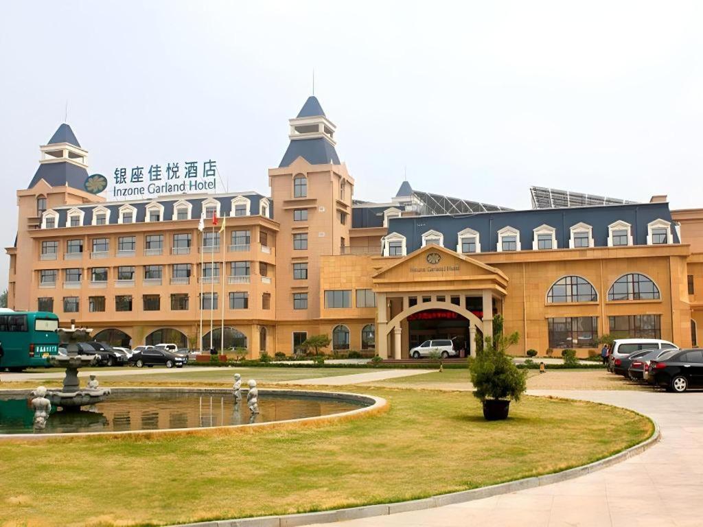 a large building with a fountain in front of it at Inzone Garland Hotel Taian in Huangqian