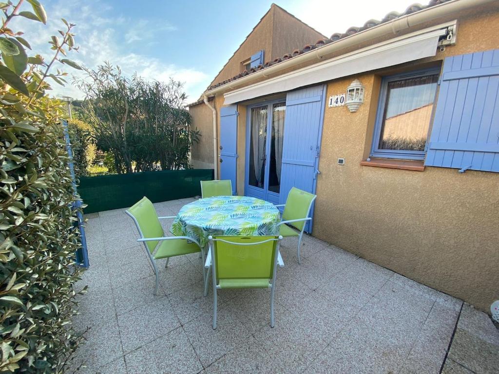 une table et des chaises assises sur une terrasse dans l'établissement Mazet avec piscine collective, au Lavandou