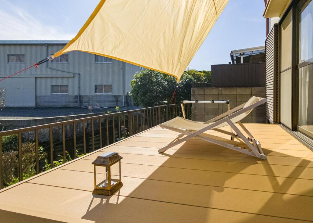 une terrasse en bois avec une chaise sur un balcon dans l'établissement ゲストハウス634庵, à Sango