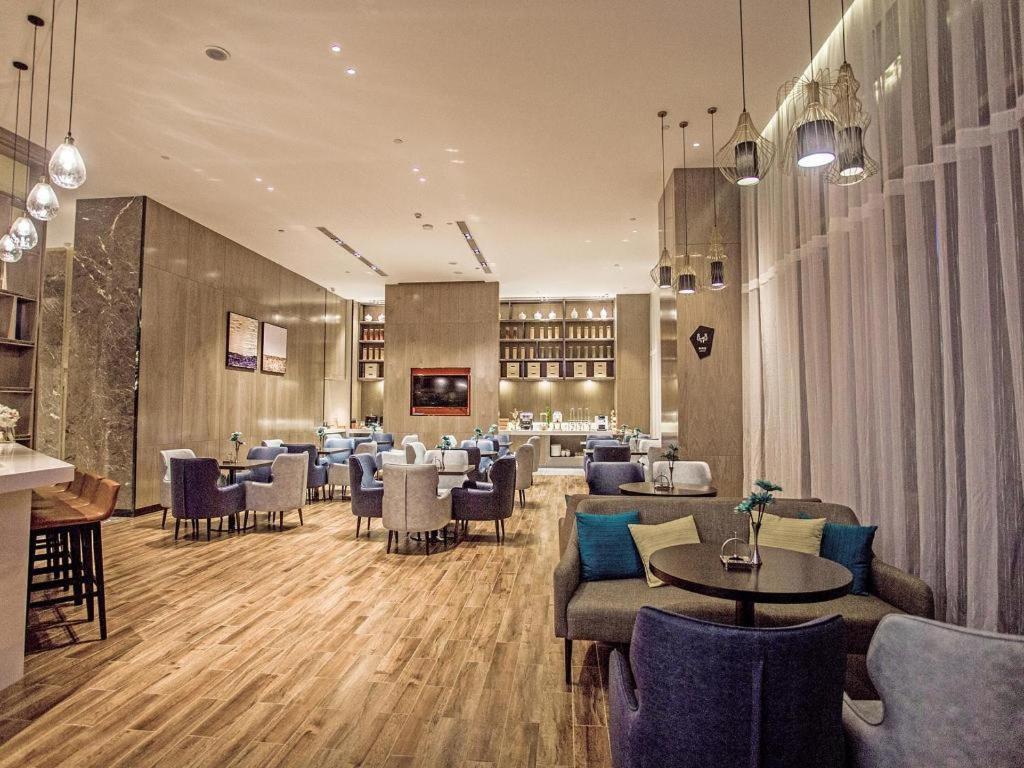 ein Restaurant mit Sofas, Tischen und Stühlen in der Unterkunft Echarm Hotel Qionghai Wanquan River in Qionghai