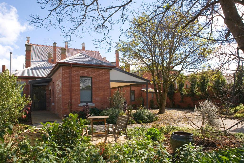 a brick house with a table and chairs in the yard at Mollisons in Kyneton