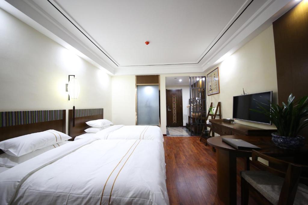 a hotel room with two beds and a flat screen tv at Yazhu Creekfront Boutique Hotel in Zhangjiajie