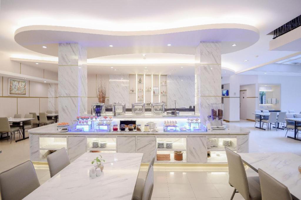 une grande cuisine avec des comptoirs blancs, des tables et des chaises dans l'établissement Grand Malioboro Yogyakarta, à Yogyakarta