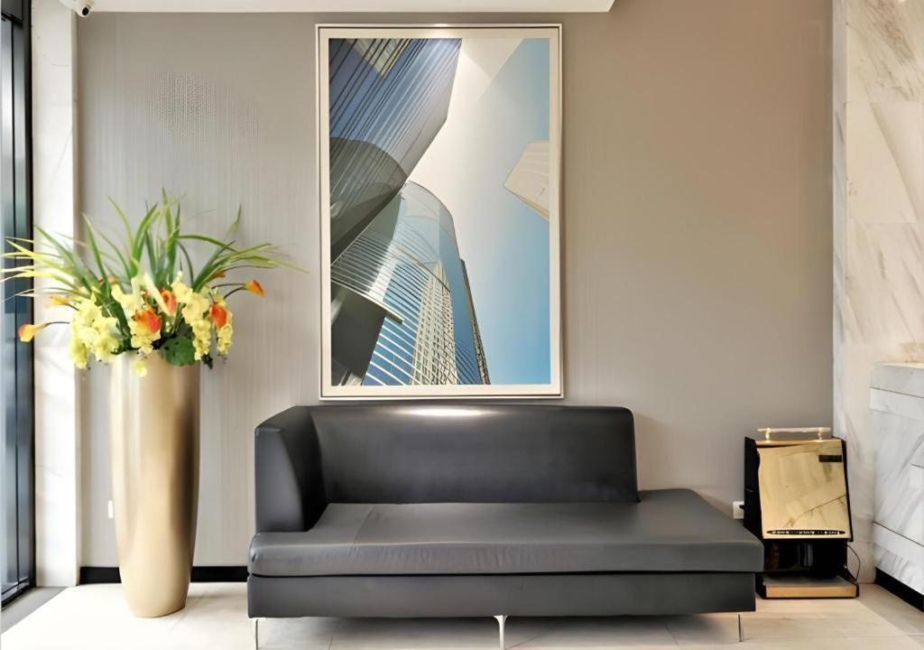 a black couch in a room with a vase of flowers at City Comfort Inn Yichang Gezhouba CBD Shopping Center in Yichang
