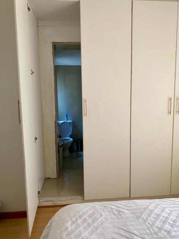 Cape TownUbuntu Guest House的一间卧室配有白色橱柜，一间浴室配有马桶