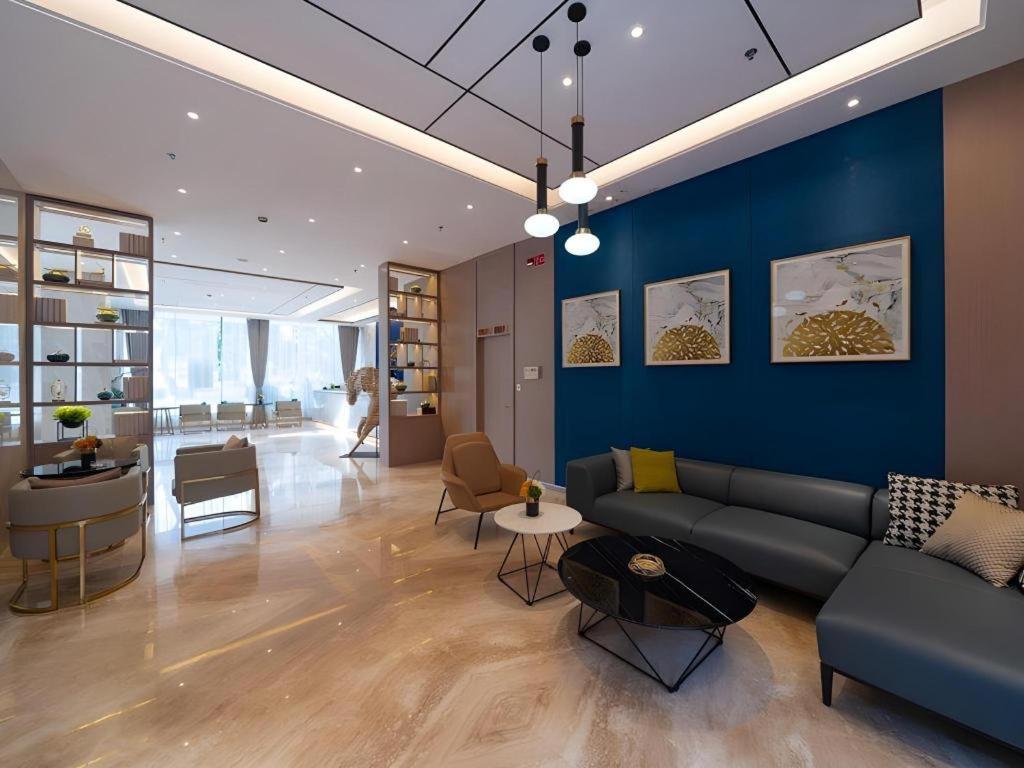 a living room with a couch and a blue wall at GreenTree Eastern Dali Railway Station Hotel in Dali