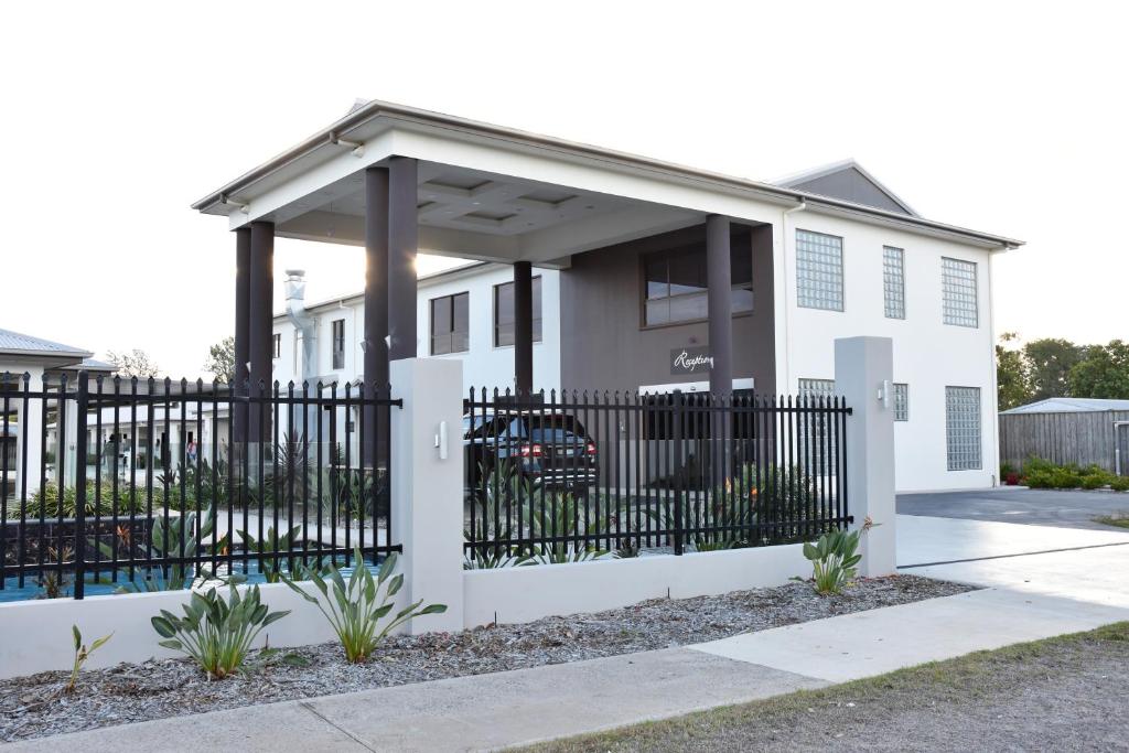 une maison blanche avec une clôture noire dans l'établissement Western Downs Motor Inn, à Miles